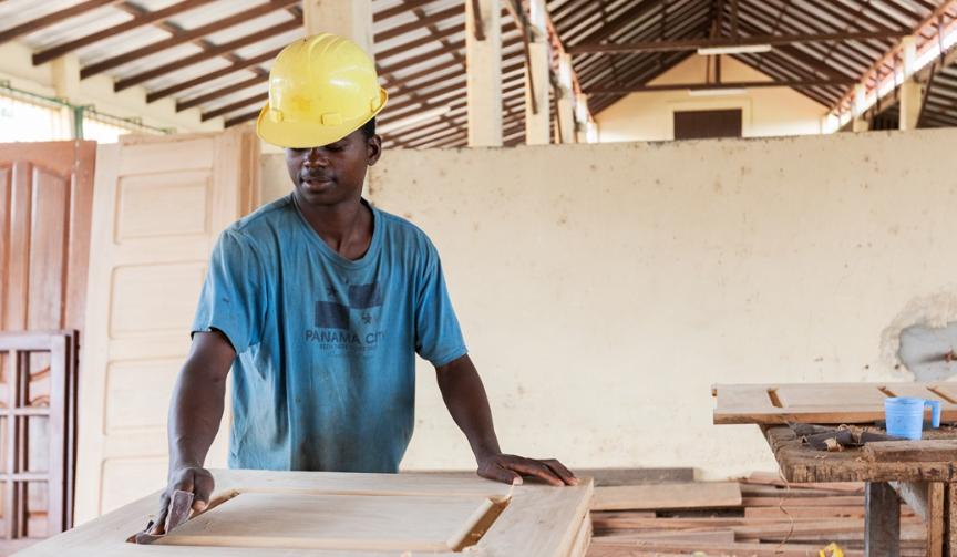 A Sasfino craftsman planing a timber board by hand